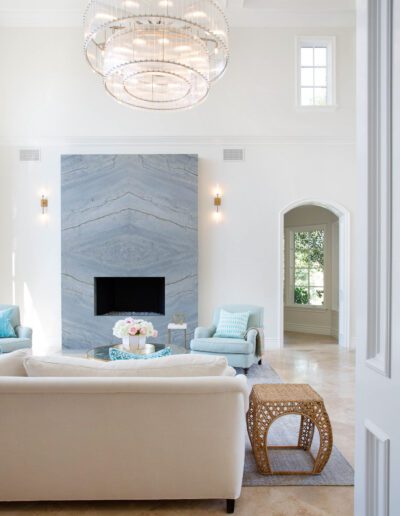 Bright living room with a white sofa, marble fireplace, and a modern chandelier.