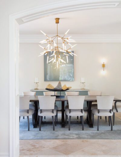 Modern dining room with a large table, elegant chairs, and a striking starburst chandelier.