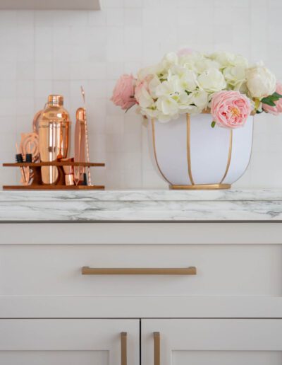 Elegant kitchen countertop with a white and gold vase of flowers and copper kitchen accessories.