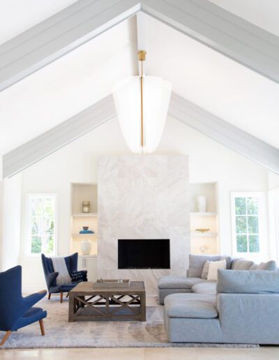 A bright and airy living room with high ceilings, a modern fireplace, and elegant furnishings.