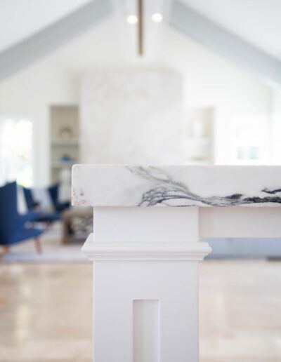 Elegant interior with a marble countertop and a glimpse of a living area featuring blue armchairs.