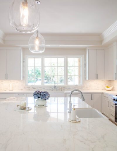 Bright, modern kitchen with marble countertops and pendant lighting.