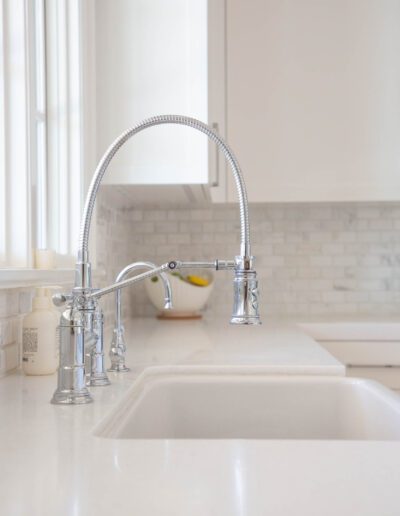 A modern kitchen sink with a flexible faucet and a bowl of lemons on the countertop.