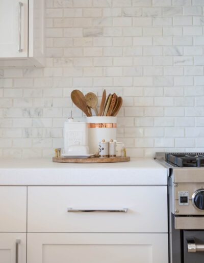 Modern kitchen with white subway tile backsplash and a set of wooden utensils in a holder on the countertop.