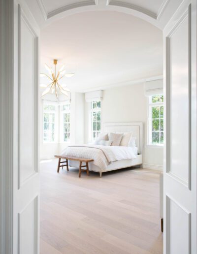 Bright and airy bedroom with minimalist design, featuring a white bedspread and a modern starburst chandelier.