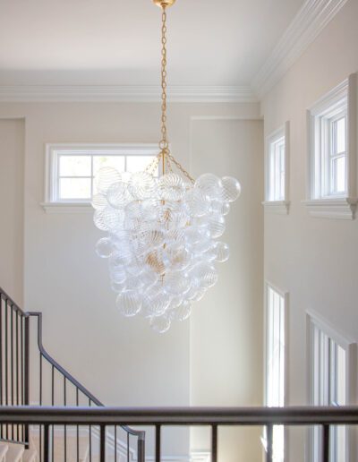 An elegant chandelier with bubble-like glass details hanging in a bright stairwell.