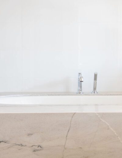 Modern bathroom with a white bathtub and sleek silver faucets, featuring herringbone tile backsplash.