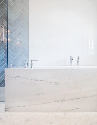 Modern bathroom interior with marble finishes and herringbone tile design.