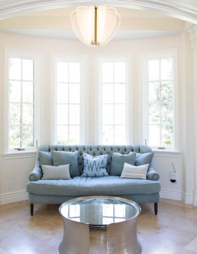 Elegant sitting area with built-in bookshelves and a light blue tufted sofa.