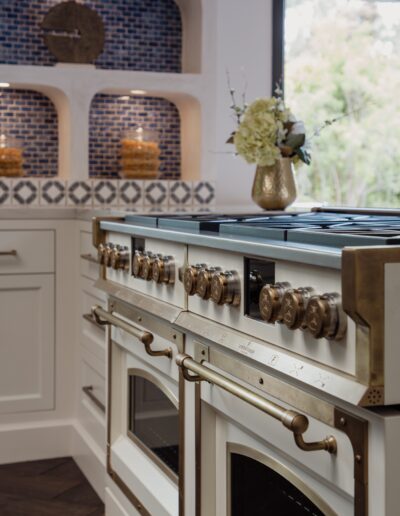 A modern kitchen with a large double oven range, decorative flower vase, and blue patterned backsplash.