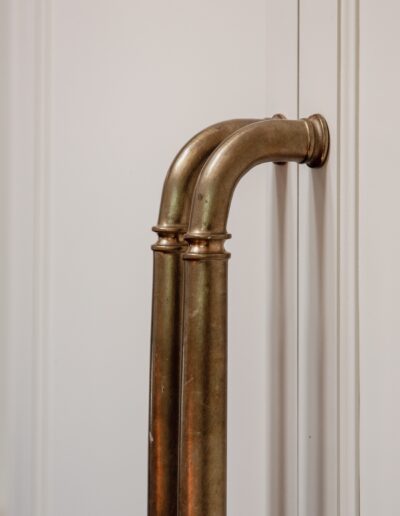 Two aged brass door handles are mounted side by side on a white paneled door, showing a slight patina.